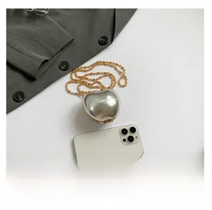 Silver mirror heart-shaped mini bag with gold bead chain shown next to a smartphone