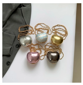 Flat lay of heart-shaped metallic evening bags in silver, gold, and pink with chain straps