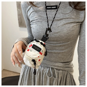 Detailed view of mini white cherry print neck pouch with fashion leather tag and strap