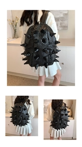 Detail of black punk backpack featuring crocodile texture and spiky cone rivet studs