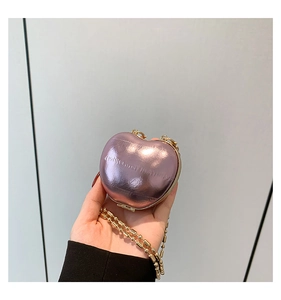 Macro detail of heart-shaped mini chain bag in pearlescent pink with gold hardware