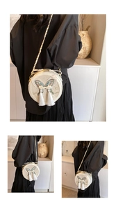 Détail d'un sac bandoulière rond chic avec broderie papillon et élégants longs glands