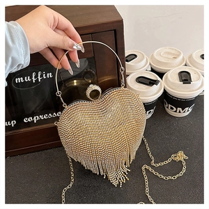 Detailed view of luxury heart-shaped evening bag featuring gold rhinestones and long tassels