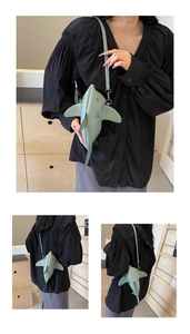 Close-up of a light green shark-shaped crossbody bag with fine leather texture and fins