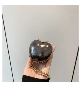 Close-up of a heart-shaped glossy crossbody bag with golden chain and metallic finish