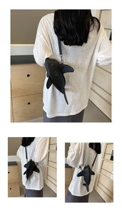 Detail view of the black shark-shaped crossbody bag with fins and leather shoulder strap