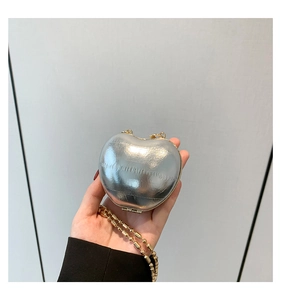 Detail of silver heart-shaped mini hardshell bag with fine gold ball chain strap