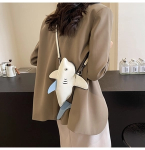 Detail of shark-shaped crossbody bag featuring light blue fins and matte leather material