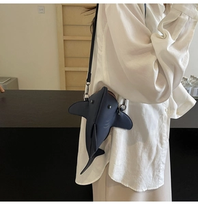 Detail of 3D shark-shaped crossbody bag featuring navy matte leather and metal buckle