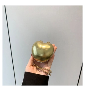 Detail of a heart-shaped gold mini bag with textured metallic finish and beaded chain