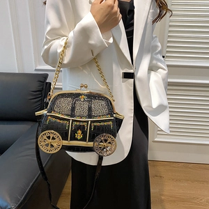 Black pumpkin carriage car bag with gold wheels and chain strap on female model