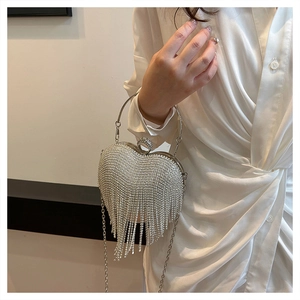 Detail of silver heart-shaped evening bag with shimmering rhinestones and tassel fringe