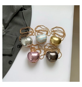 Detailed view of heart-shaped mini crossbody bags in metallic colors with gold bead chains