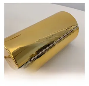 Detail show of golden cylindrical acrylic evening bag with polished metal hinge and chain