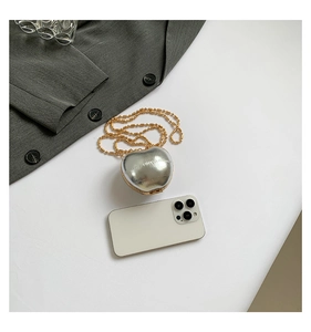 Mini silver heart crossbody bag with gold beaded chain shown next to a smartphone