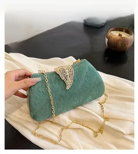 Detail of emerald green pleated evening bag with gold floral clasp and chain strap