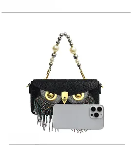 Macro detail of owl-shaped crystal handbag with colorful bead fringe and phone for scale