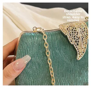 Detail of dark green evening bag with shimmering texture and golden leaf clasp