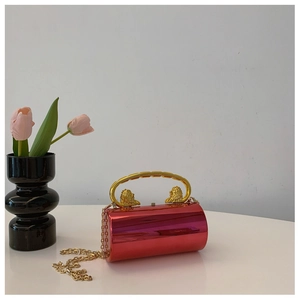 Macro view of red mirror finish cylinder clutch with gold lion handle and chain