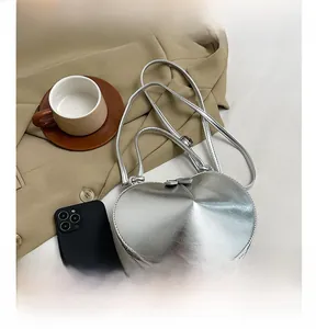 Detail of silver heart-shaped crossbody bag with adjustable straps and metallic finish