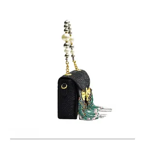 Detail view of owl cross-body bag with pearl handle and colorful beaded tassels