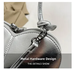 Detail of silver heart-shaped bag showing metal zipper and knotted shoulder strap