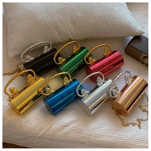 Macro detail of glossy metallic cylindrical bags with ornate lion head handle accents