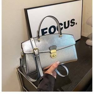 Detailed view of silver tote bag with snakeskin texture and golden metal lock buckle