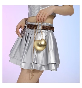 Detail of a heart-shaped gold metallic mini chain bag styled with a Y2K silver outfit