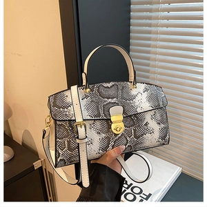 Detail of snake print tote bag with golden twist lock and adjustable shoulder strap
