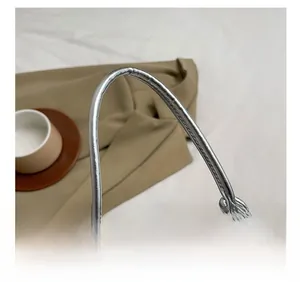 Detail shot of the silver handbag handle with decorative knot and smooth metal zipper