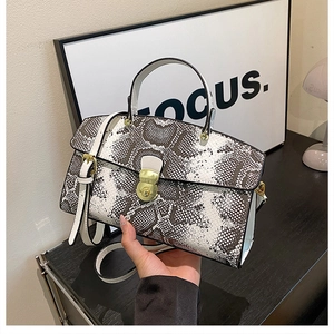Detailed close-up of snake print tote bag with golden metal clasp and top handle