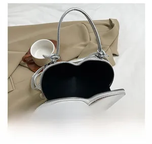 Detail view of the silver heart-shaped bag showing internal storage and metal zipper