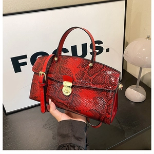 Detail of red snake pattern tote bag featuring gold twist lock and fine texture