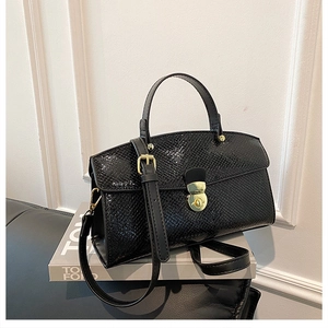 Detailed view of the black snake pattern leather texture and gold metallic twist lock