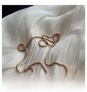 Detail of a golden snake bone chain strap on white silk for transparent jelly bags