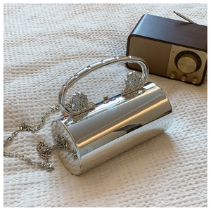 Detail view of silver cylindrical bag with mirror finish and lion head metal handles
