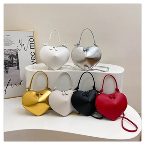 Detail of trendy heart-shaped crossbody bags in various colors with leaf-shaped zippers