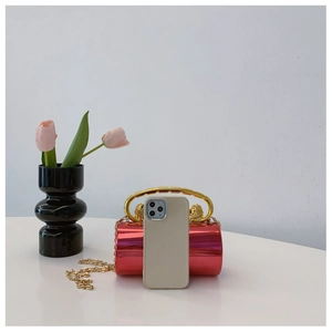 Metallic red cylinder handbag featuring gold handle and chain with phone for scale