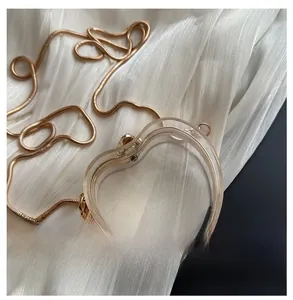 Detail view of heart-shaped transparent acrylic bag with golden snake chain strap