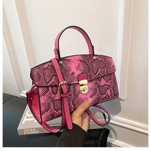 Detail of fuchsia snakeskin tote bag with golden twist lock and adjustable strap