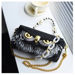 Macro shot of owl-shaped clutch with rhinestones, pearl handle, and dual chains