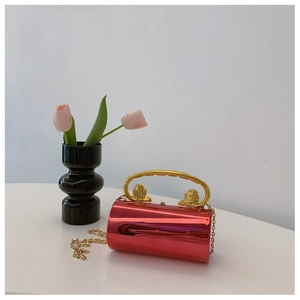 Macro detail of red mirror cylinder bag with golden lion head relief and semicircular handle