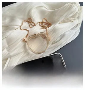 Detail of heart-shaped transparent acrylic mini bag with elegant gold chain strap