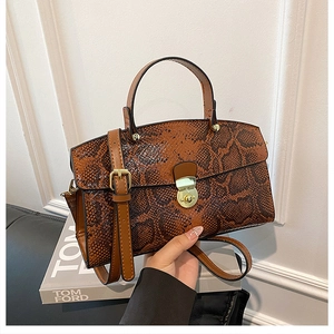 Detail of snakeskin embossed PU tote bag featuring a gold cylindrical buckle and crossbody strap