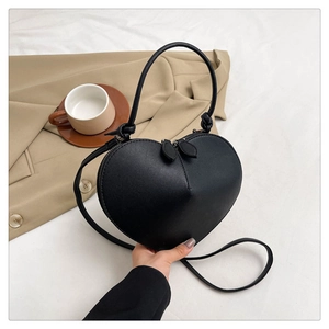 Detail showing the 3D heart-shaped black leather handbag with a stylish metal leaf zipper