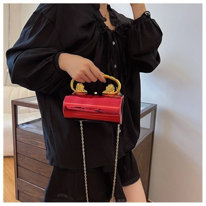Detail of red acrylic cylindrical bag with golden lion head handles and chain strap