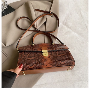 Detail of brown snakeskin pattern tote bag with gold lock buckle and fine shoulder strap