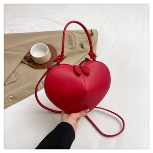 Detail of red heart-shaped PU leather bag with top handle and double zipper closure
