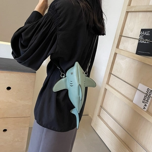 Cute shark-shaped crossbody bag in mint green leather shown on model in a modern room